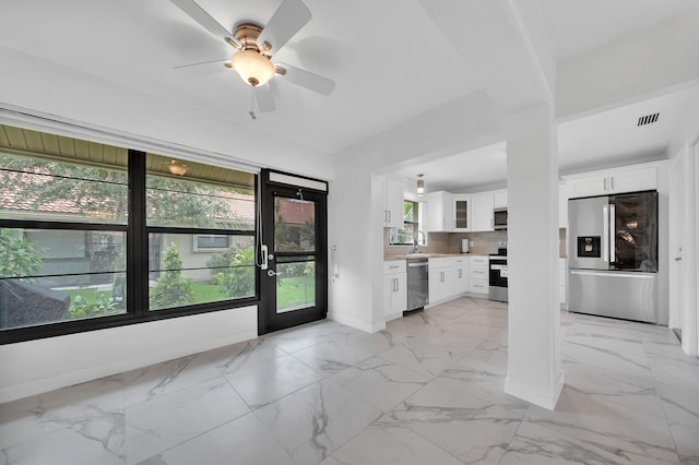 kitchen featuring appliances with stainless steel finishes, a wealth of natural light, white cabinetry, and tasteful backsplash