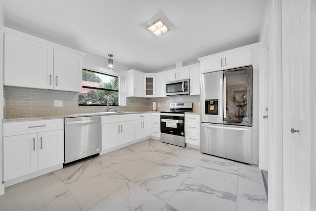 kitchen with sink, tasteful backsplash, white cabinetry, appliances with stainless steel finishes, and light stone countertops