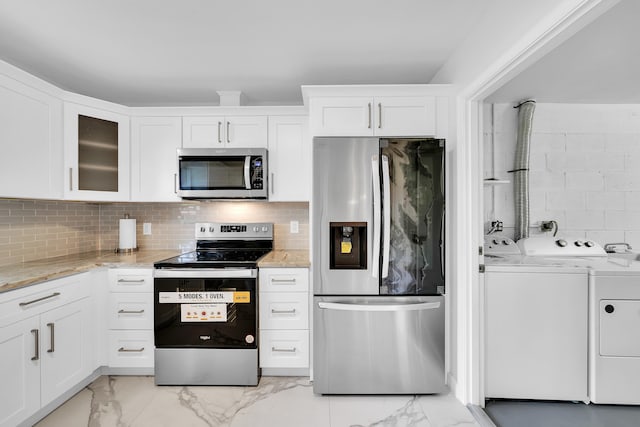 kitchen with light stone counters, white cabinets, tasteful backsplash, stainless steel appliances, and washer and dryer