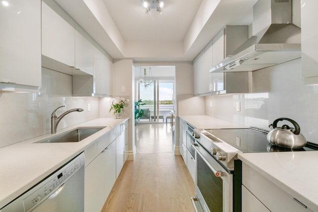 kitchen with sink, stainless steel electric range oven, wall chimney exhaust hood, and white cabinetry