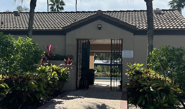 entrance to property featuring a tiled roof and stucco siding