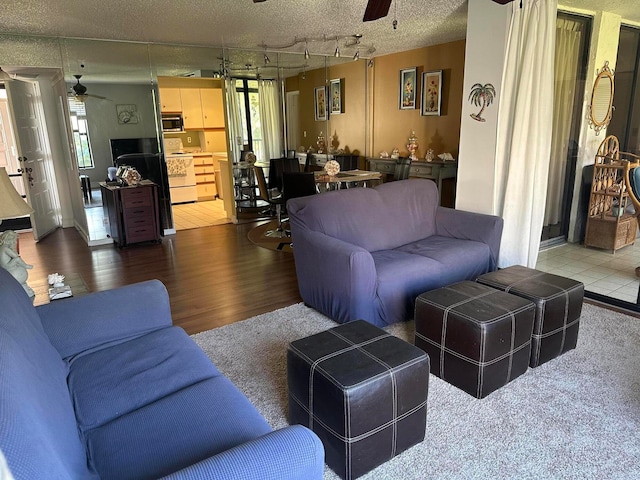 living room with track lighting, hardwood / wood-style flooring, ceiling fan, and a textured ceiling