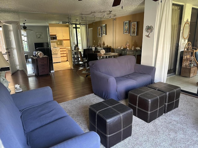 living room featuring ceiling fan, track lighting, a textured ceiling, and wood finished floors