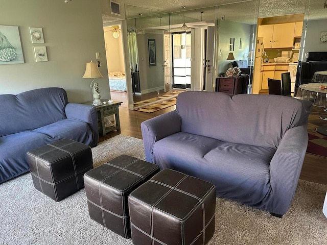 living room with ceiling fan, hardwood / wood-style floors, and a textured ceiling