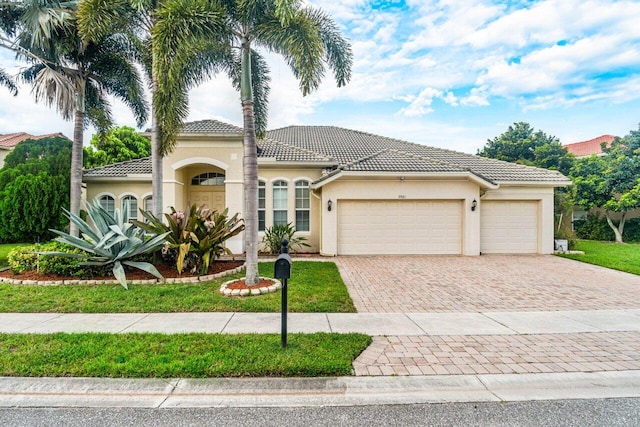 mediterranean / spanish house featuring a garage and a front lawn