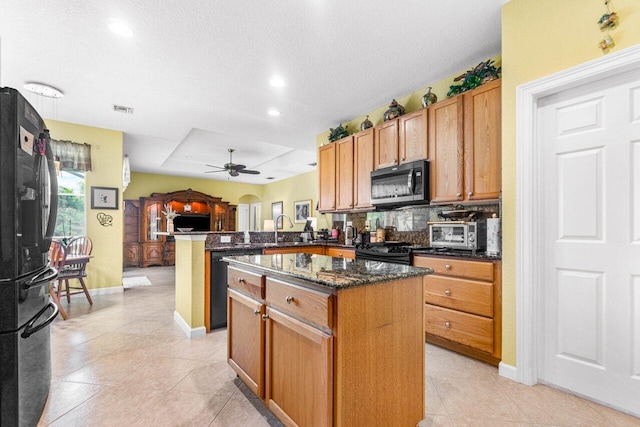 kitchen with ceiling fan, kitchen peninsula, a kitchen island, a textured ceiling, and black appliances