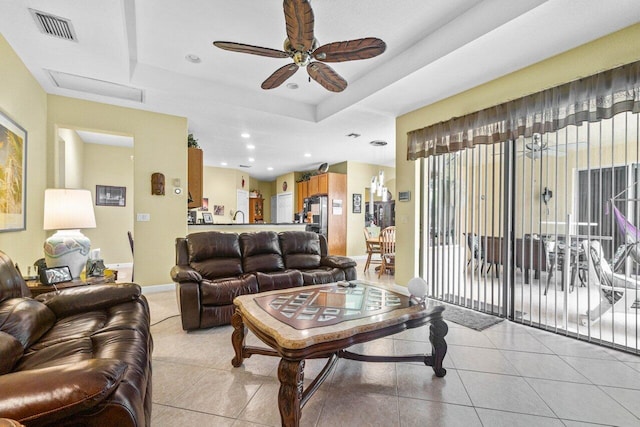 living room featuring ceiling fan, a raised ceiling, and light tile patterned floors