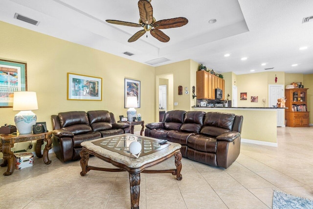 tiled living room featuring a raised ceiling and ceiling fan