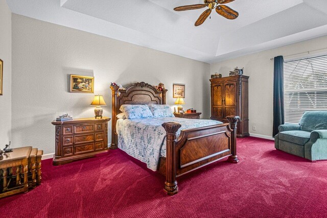 bedroom featuring carpet floors, a tray ceiling, and ceiling fan