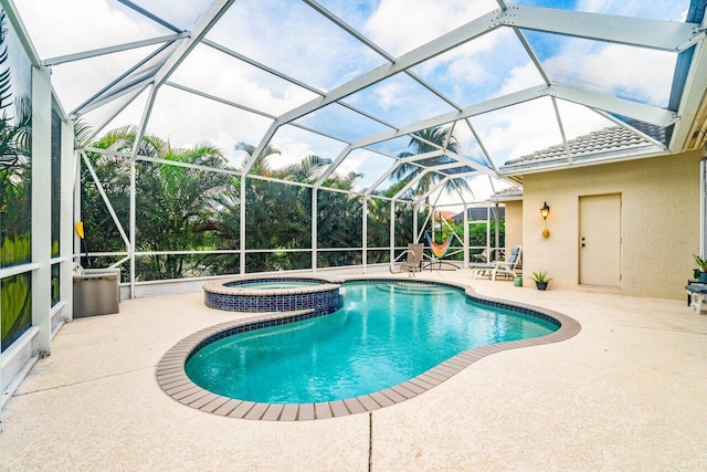 view of pool with glass enclosure, an in ground hot tub, and a patio area