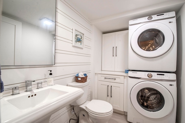 bathroom with stacked washer and dryer, sink, and toilet