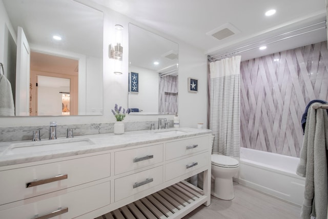 full bathroom with hardwood / wood-style floors, vanity, shower / bath combo with shower curtain, and toilet