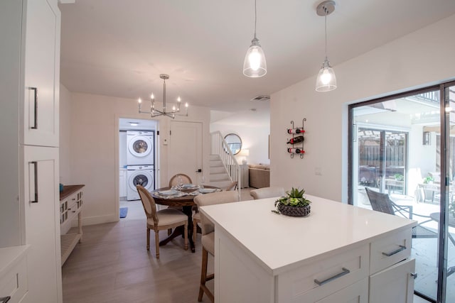 kitchen featuring a center island, light wood-type flooring, white cabinetry, and stacked washing maching and dryer