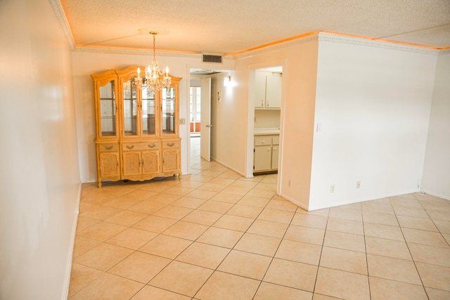 unfurnished dining area featuring light tile patterned floors, a textured ceiling, ornamental molding, and a chandelier