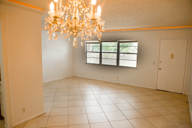 tiled empty room featuring a textured ceiling and an inviting chandelier