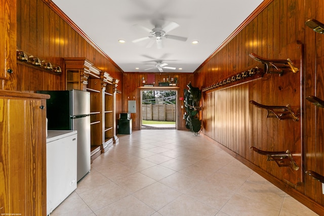 kitchen featuring ceiling fan, wood walls, and ornamental molding