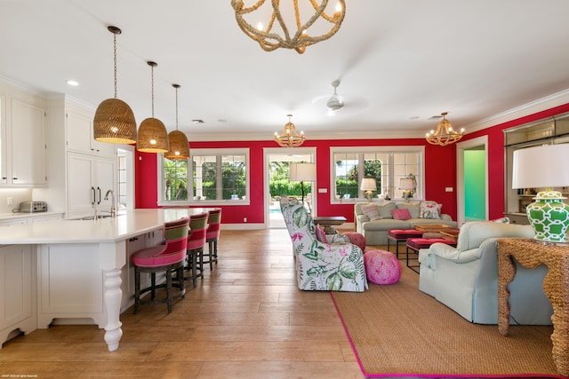 living room with light hardwood / wood-style flooring, ornamental molding, and sink