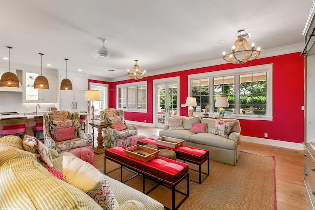 living room with ornamental molding, sink, ceiling fan with notable chandelier, and light wood-type flooring