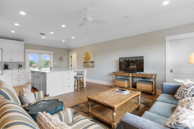 living room featuring ceiling fan, sink, and light wood-type flooring