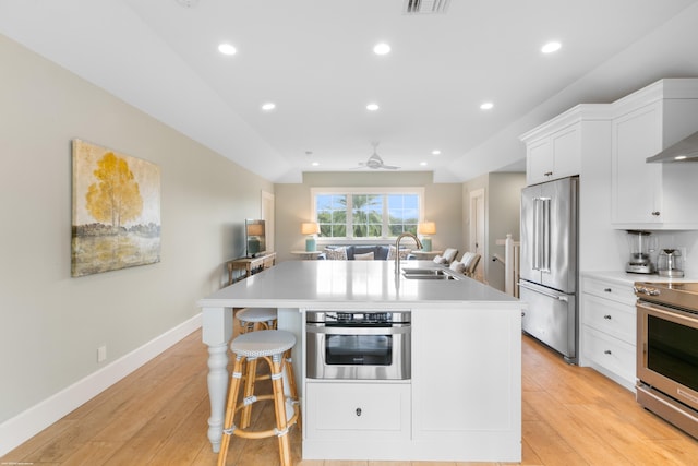 kitchen featuring an island with sink, light hardwood / wood-style flooring, stainless steel appliances, sink, and white cabinetry