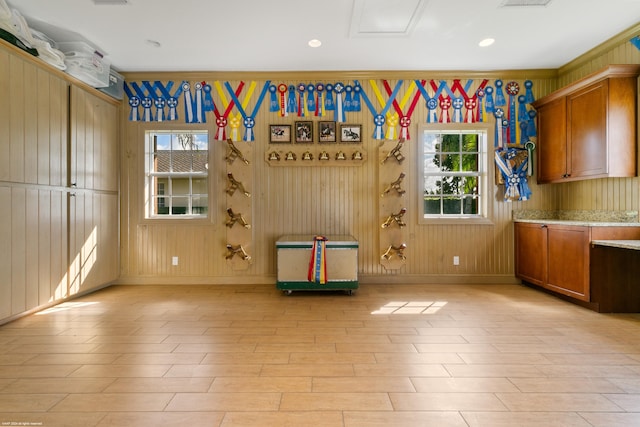 interior space with crown molding, wood walls, and light hardwood / wood-style flooring