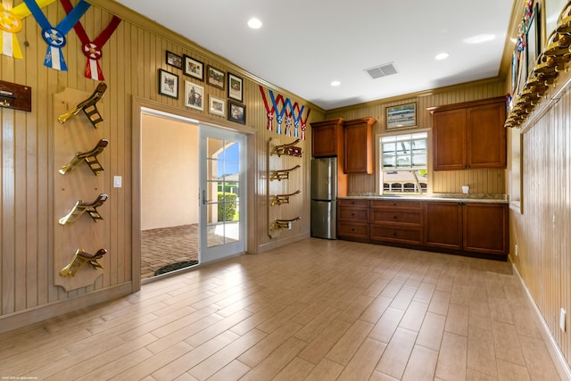 kitchen featuring wooden walls, light wood-type flooring, and stainless steel refrigerator