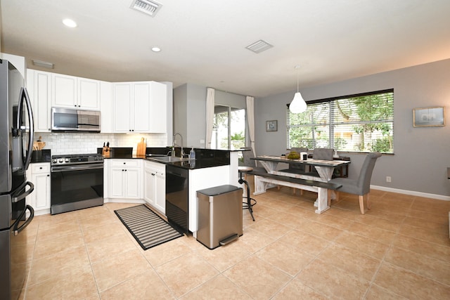 kitchen with stainless steel appliances, white cabinets, kitchen peninsula, hanging light fixtures, and sink