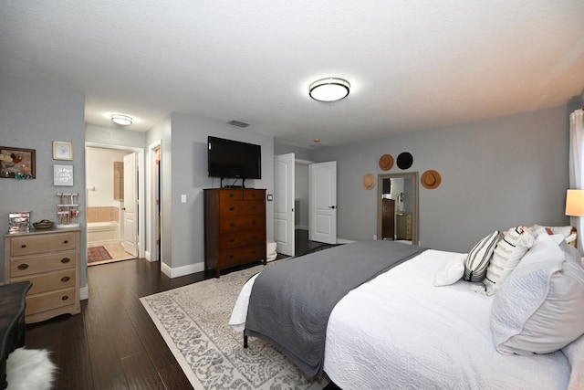 bedroom featuring dark wood-type flooring and ensuite bath