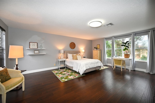 bedroom featuring a textured ceiling and dark hardwood / wood-style flooring