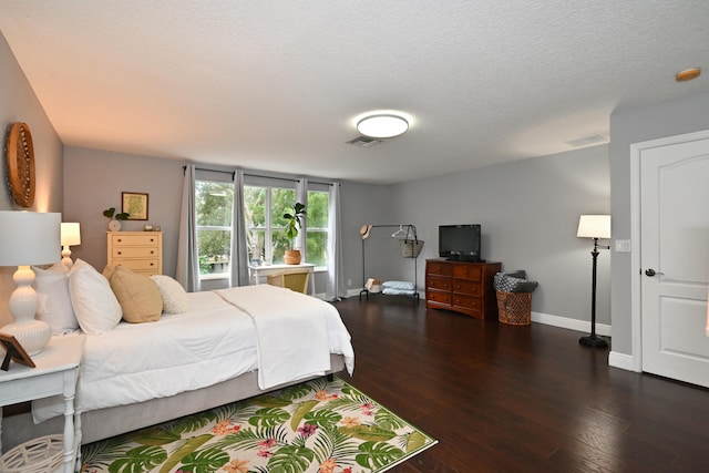 bedroom with dark hardwood / wood-style floors and a textured ceiling