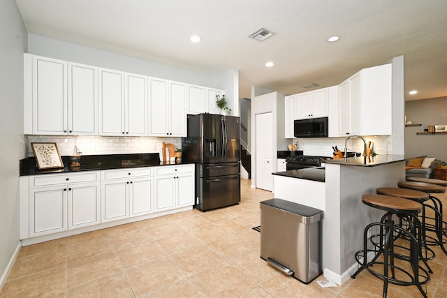 kitchen featuring a breakfast bar area, white cabinetry, black appliances, and kitchen peninsula