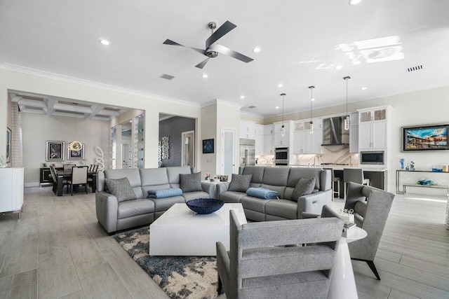 living room with light wood-type flooring, ceiling fan, sink, and crown molding