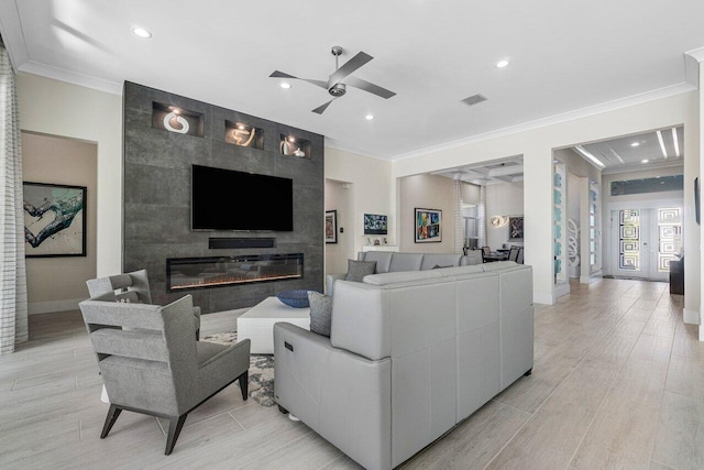 living room featuring ornamental molding, ceiling fan, light hardwood / wood-style flooring, and a fireplace