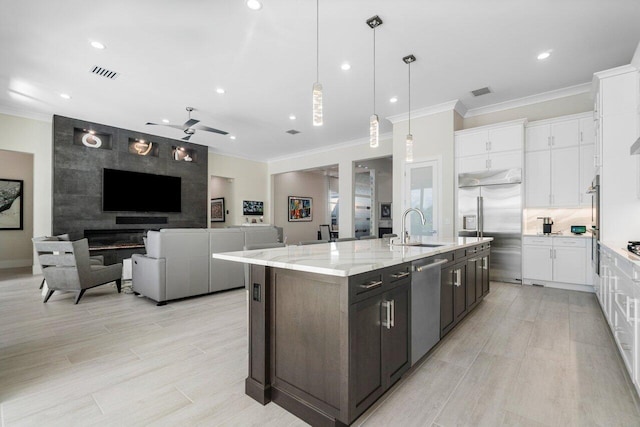 kitchen with white cabinets, hanging light fixtures, sink, appliances with stainless steel finishes, and light stone countertops