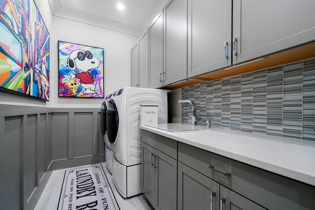 clothes washing area featuring cabinets, sink, light hardwood / wood-style flooring, independent washer and dryer, and ornamental molding