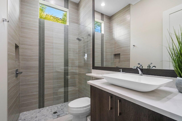 bathroom with vanity, toilet, and tiled shower