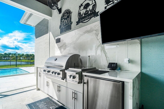 view of patio / terrace with an outdoor kitchen, a fenced in pool, and a grill