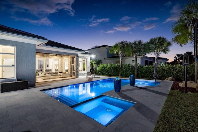 pool at dusk with an in ground hot tub, outdoor lounge area, and a patio area