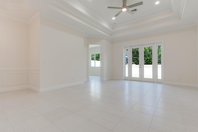 empty room featuring french doors, a tray ceiling, and crown molding