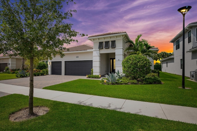 view of front of property with a garage, a yard, and central AC unit