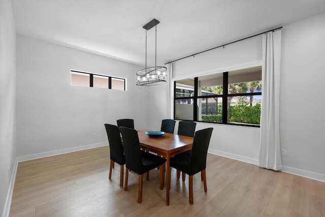 dining area with a wealth of natural light, an inviting chandelier, and light hardwood / wood-style flooring