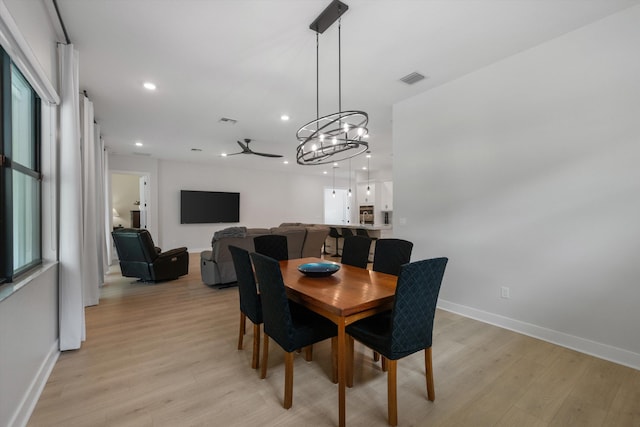 dining area featuring ceiling fan with notable chandelier and light hardwood / wood-style flooring