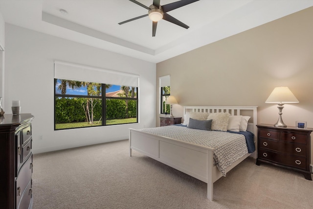 bedroom featuring ceiling fan, a raised ceiling, and light carpet