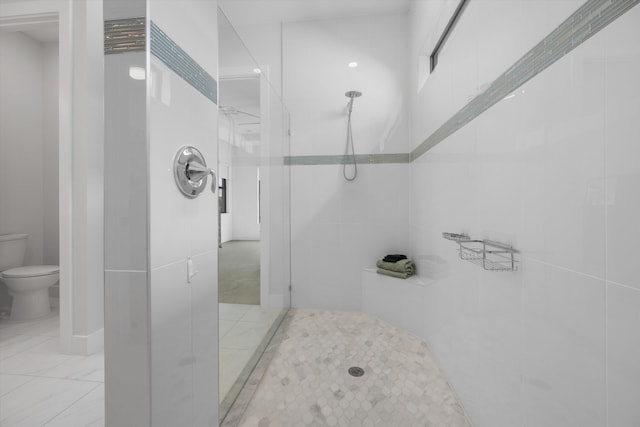 bathroom featuring a tile shower, tile walls, and toilet