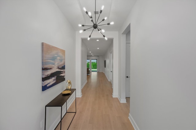 corridor with light hardwood / wood-style flooring and a chandelier