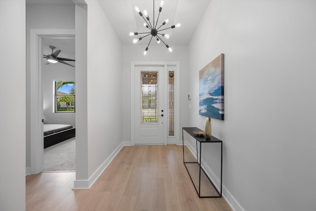 entryway featuring ceiling fan with notable chandelier and light hardwood / wood-style floors