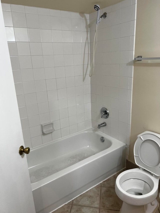 bathroom featuring tiled shower / bath combo, toilet, and tile patterned floors