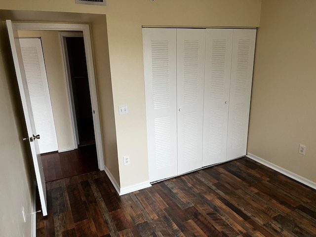 unfurnished bedroom featuring a closet and dark wood-type flooring