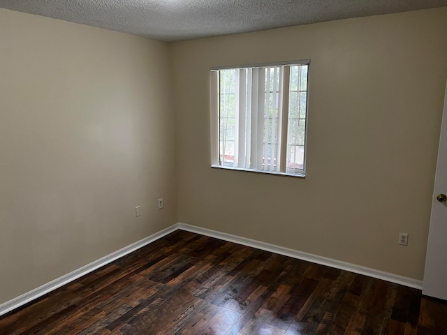 spare room featuring a textured ceiling and dark hardwood / wood-style floors