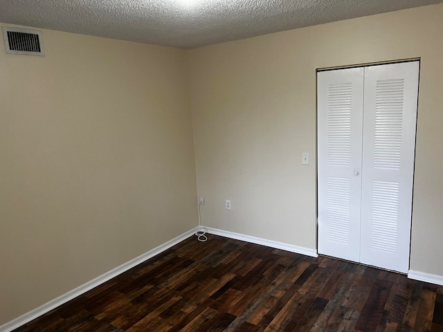 unfurnished bedroom with a closet, a textured ceiling, and dark hardwood / wood-style floors